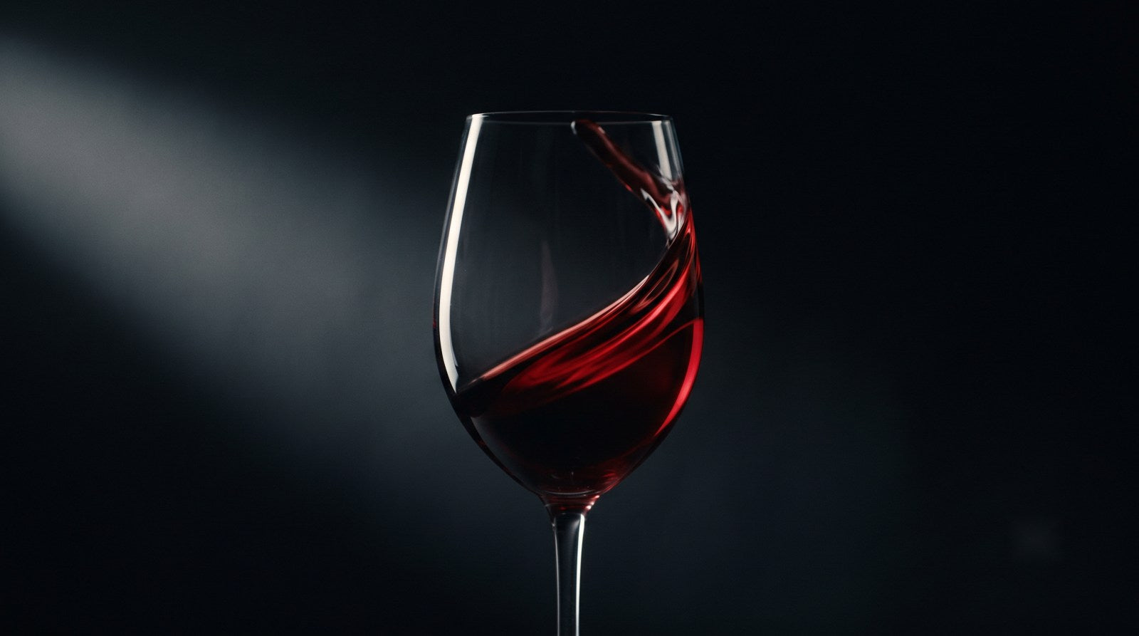 Taça de vinho tinto em movimento sobre fundo escuro