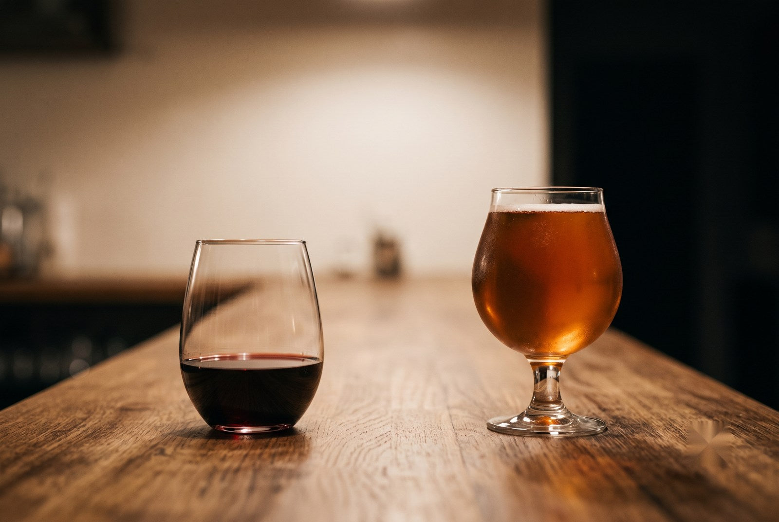 Taça de vinho tinto ao lado de uma cerveja artesanal